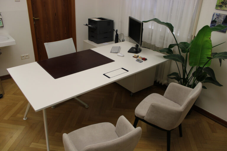 Ein moderner Schreibtisch mit zwei Stühlen und einem Computer in einem Büro.