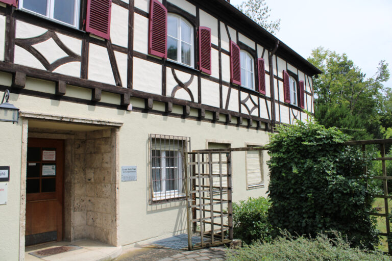 Eingang zur Praxis Dr. Tobias Meile mit Holzverkleidung und Fenstern mit roten Fensterläden.